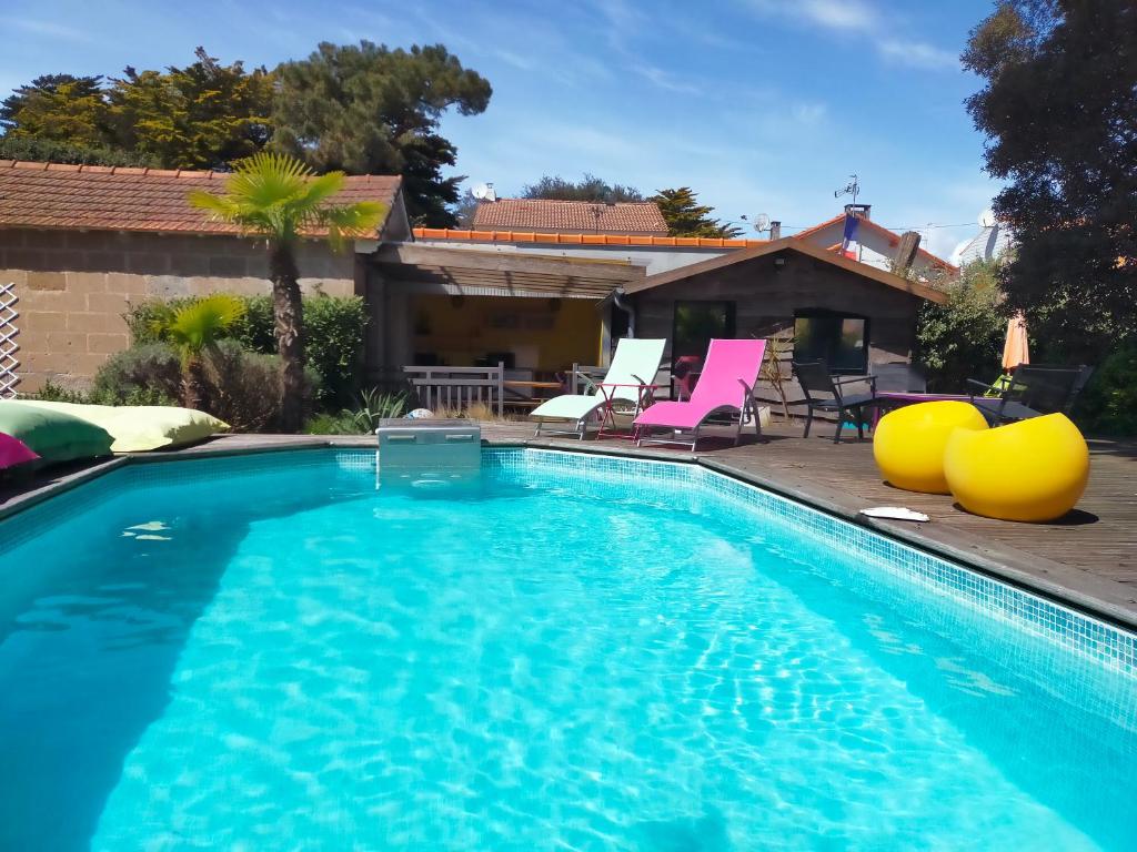 - une piscine avec des chaises et une maison dans l'établissement Le Gage location de vacance à la semaine, à Saint-Brévin-lʼOcéan