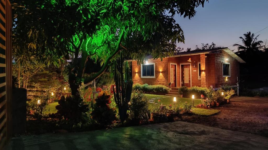 une maison éclairée dans un jardin la nuit dans l'établissement The Royal Ascot Holiday Home, à Alibaug