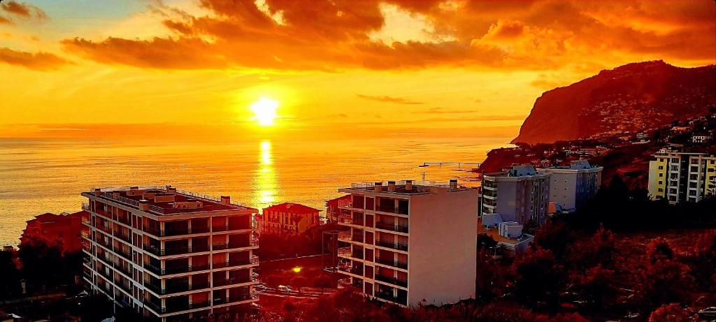 una puesta de sol sobre una ciudad con un edificio y el océano en Horizon Dream, en Funchal