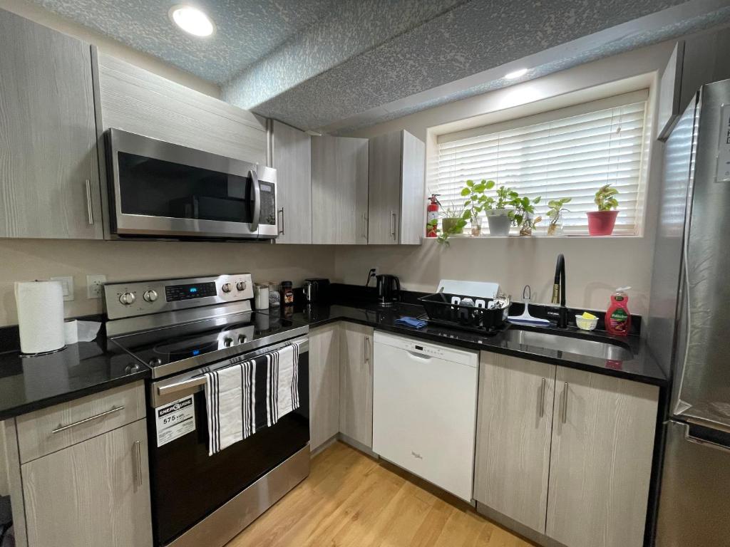 a kitchen with a stove and a microwave at Super Luxury & Cozy Lower Level Apartment in NW Calgary, AB Close to Banff in Calgary