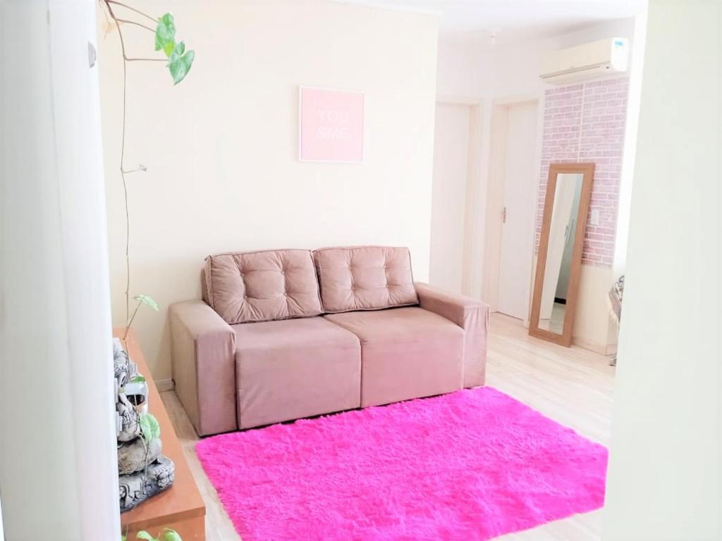 Sofá rosa en la sala de estar con alfombra rosa en Pôr do Sol 8 andar en Canoas