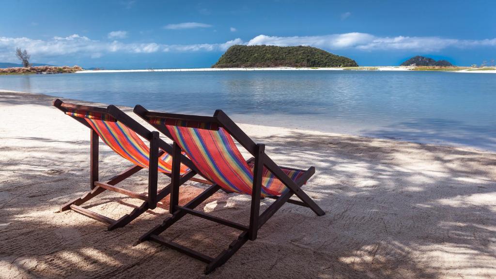 a rocking chair sitting on a beach near the water at Baan Manali Resort in Thongsala