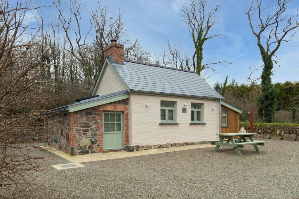 ein kleines Cottage mit einem Picknicktisch davor in der Unterkunft The Woodland Retreat Pembrokeshire Dog-friendly in Haverfordwest
