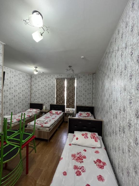 a room with two beds and two tables in it at Iso Hostel in Tashkent