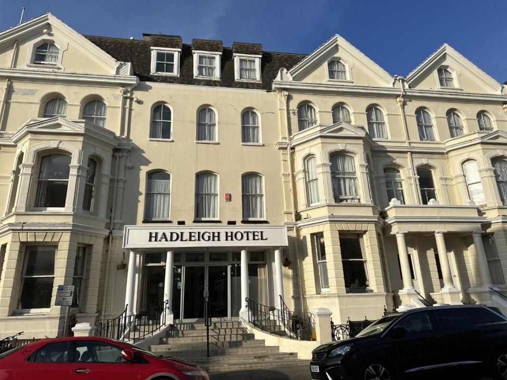 ein großes weißes Gebäude mit einem Schild davor in der Unterkunft Hadleigh Hotel in Eastbourne