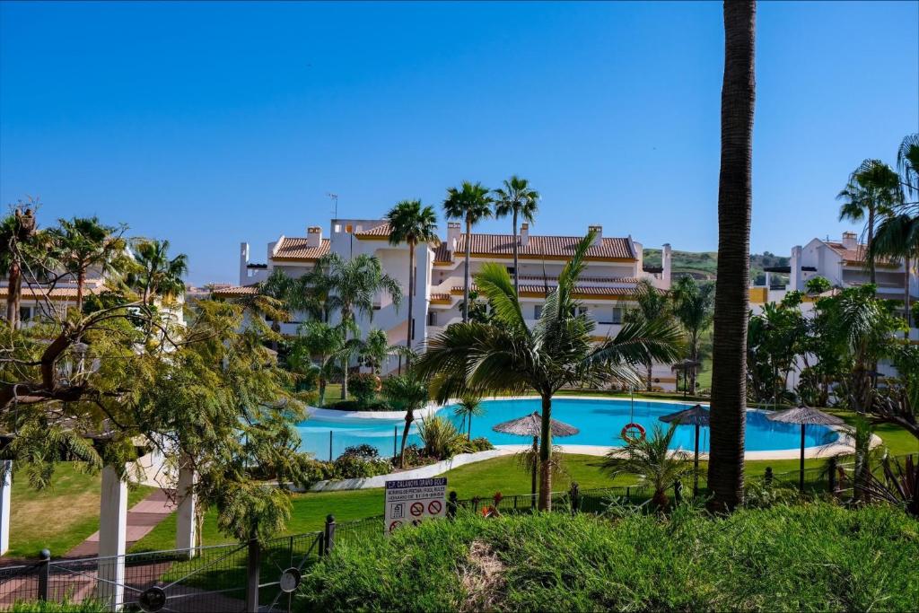 een groot zwembad in een resort met palmbomen bij Casa Jilou in Mijas Costa