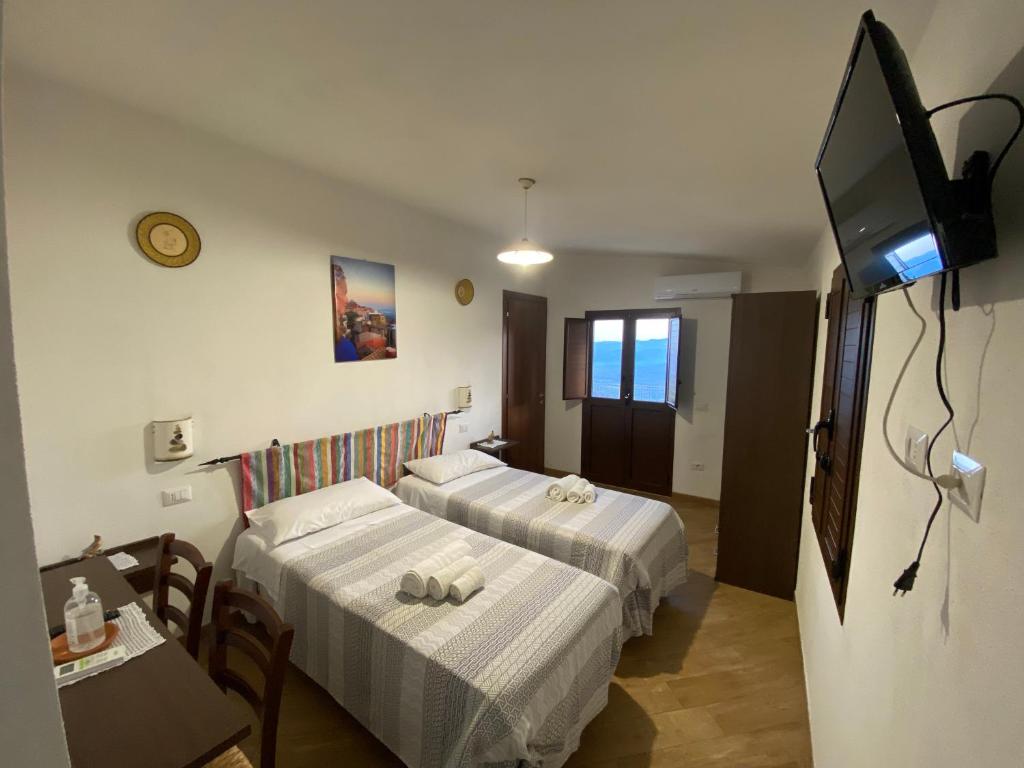 a hotel room with two beds and a flat screen tv at B&b Boladina Experience in Baunei