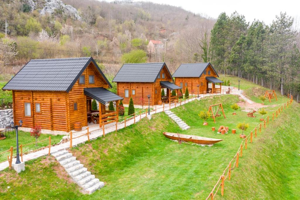 un grupo de cabañas de madera en un campo de hierba en FOREST&LAKE COTTAGES en Virpazar