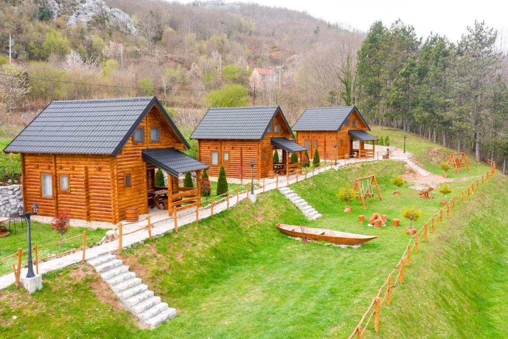 a group of wooden cabins on a grass field at FOREST&LAKE COTTAGES in Virpazar