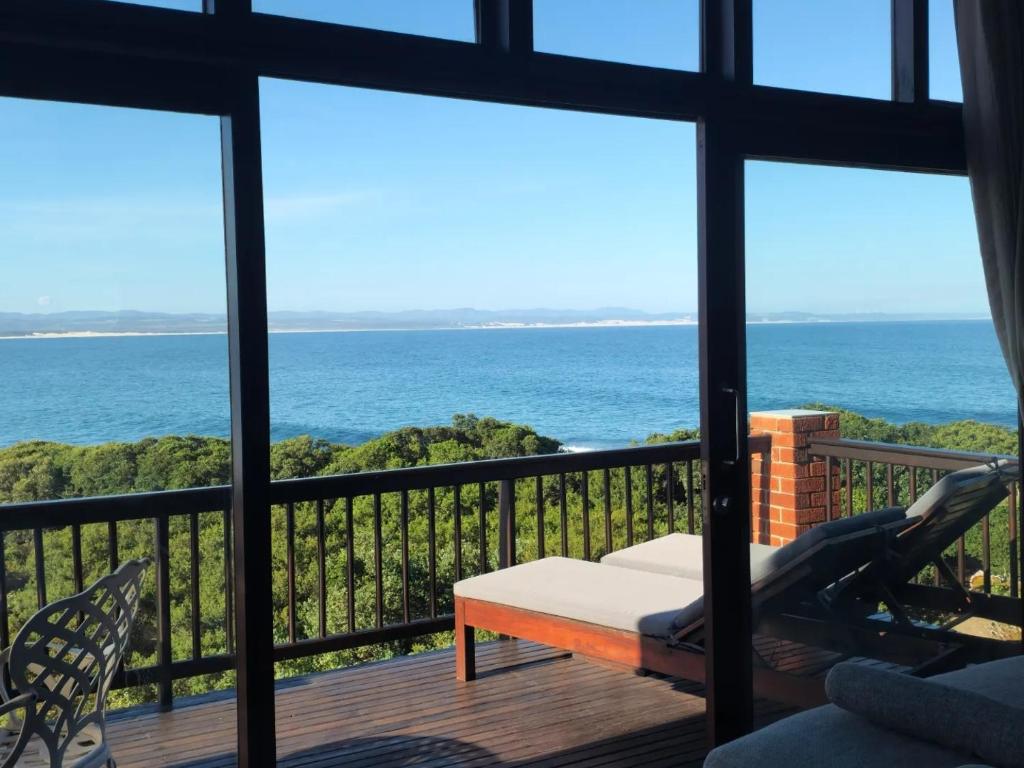 a room with a view of the ocean from a balcony at Shaloha Guesthouse on Supertubes in Jeffreys Bay