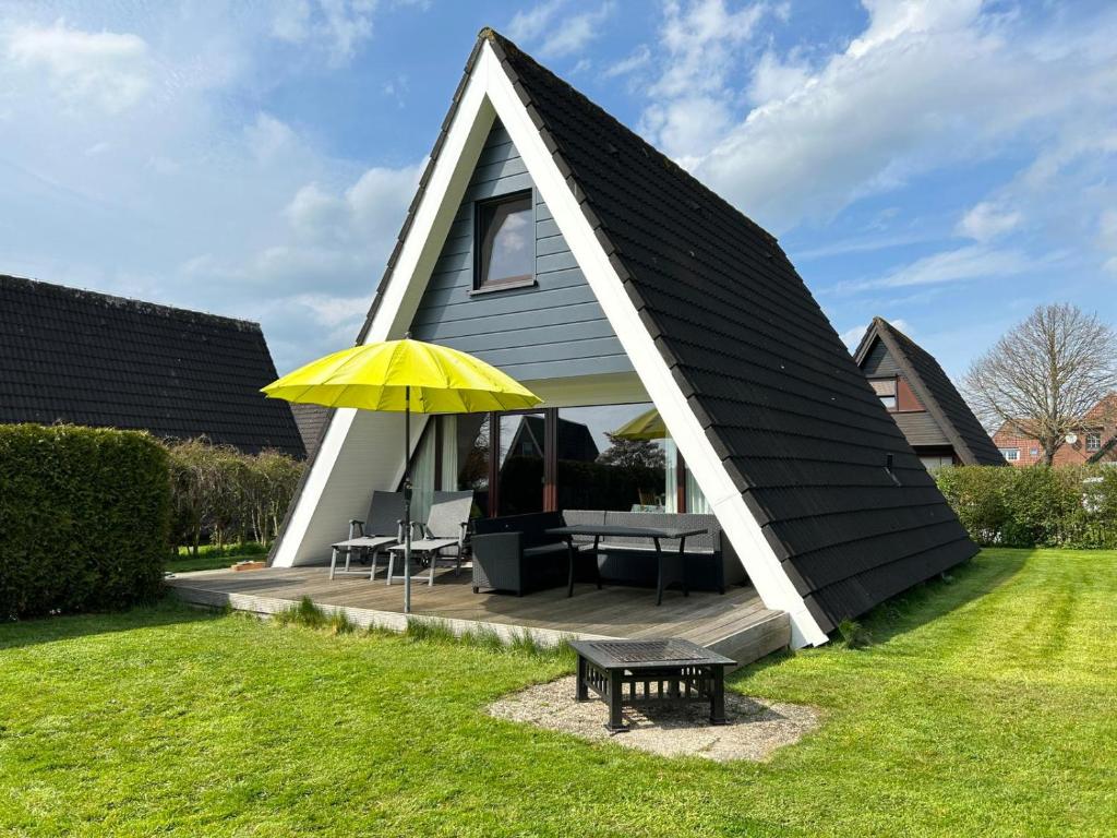 ein kleines Haus mit einem Tisch und einem gelben Regenschirm in der Unterkunft Haus Blume in Carolinensiel