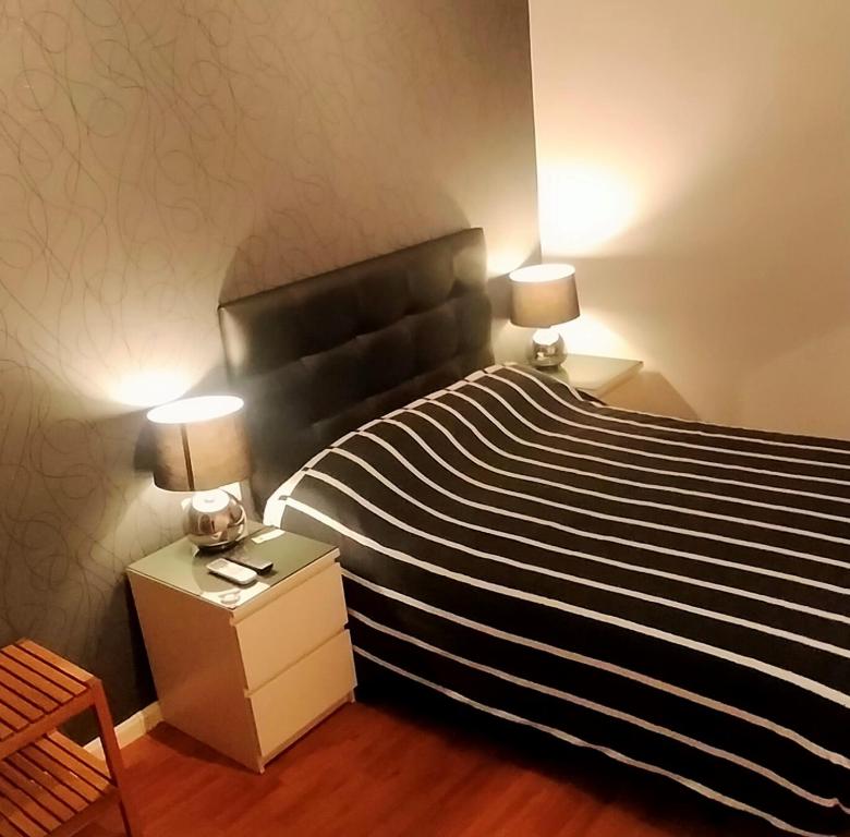 1 dormitorio con 1 cama de rayas en blanco y negro con 2 lámparas en SINGLE ROOMS en Madrid