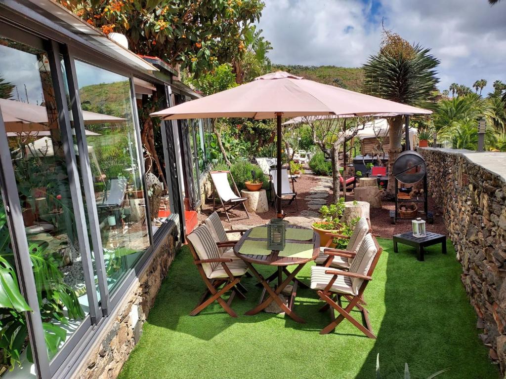 a patio with a table and chairs and an umbrella at Casa Finca Doñana in Arucas