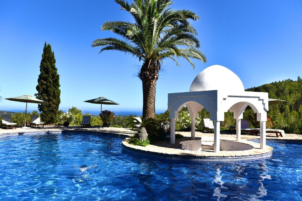 una piscina en un complejo con una palmera en Seven Senses Luxury Hilltop villa with sea views, en Santa Eulària des Riu
