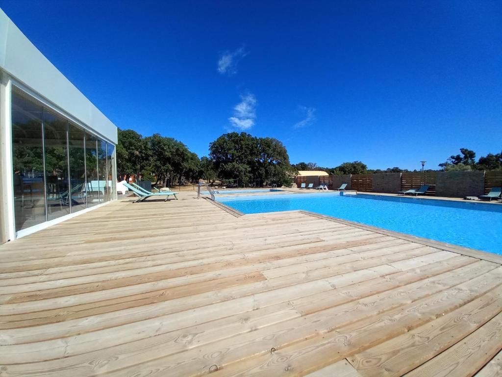 une terrasse en bois à côté d'une piscine dans l'établissement Appartement en résidence 3☆ , n°85, à Lecci