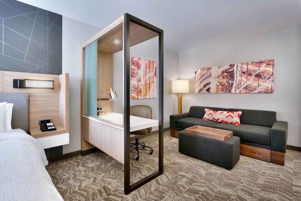 a hotel room with a bed and a couch and a mirror at SpringHill Suites by Marriott Salt Lake City Sugar House in Salt Lake City