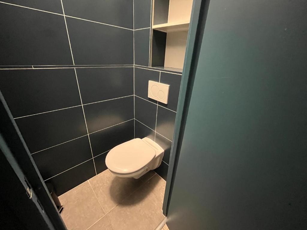 a bathroom with a toilet and a blue tiled wall at Appartement Prestige - Amiens in Amiens