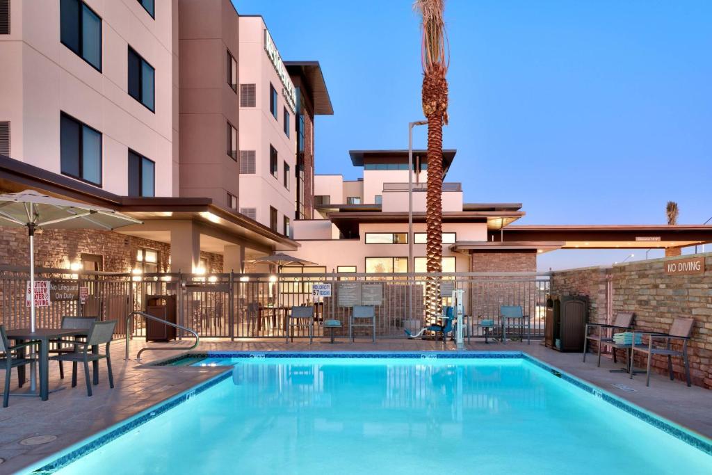 una piscina con mesas y sillas junto a un edificio en Residence Inn by Marriott Phoenix West/Avondale, en Avondale