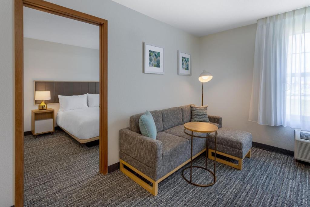 um quarto de hotel com um sofá, uma cama e um espelho em TownePlace Suites New Orleans Metairie em Harahan