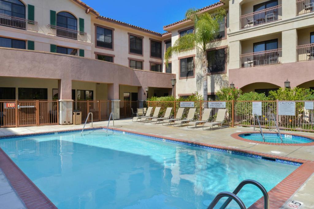 une piscine avec des chaises et un bâtiment dans l'établissement Courtyard Thousand Oaks Ventura County, à Thousand Oaks