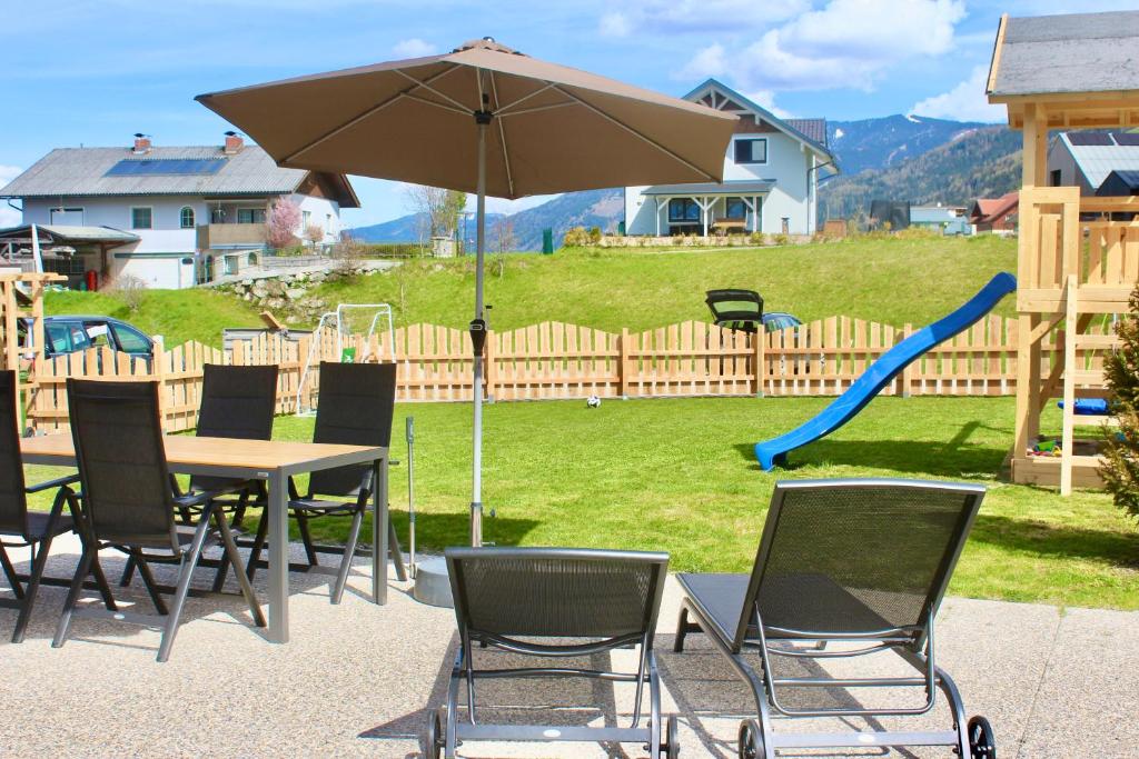 a table and chairs with an umbrella and a playground at Chalet Mama in Pruggern