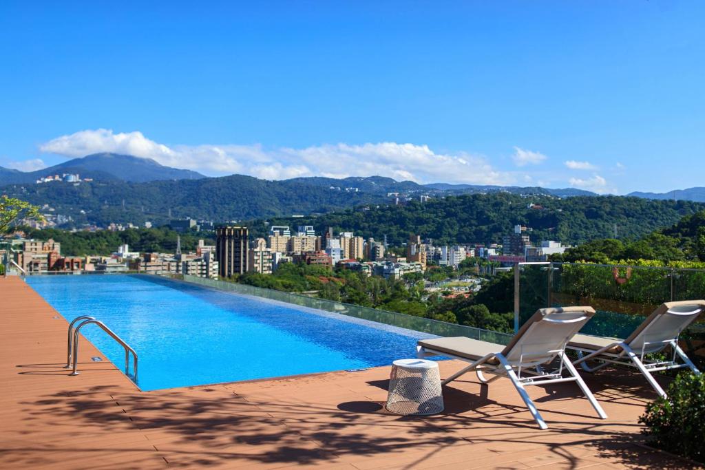 a swimming pool with two chairs and a city at Renaissance Taipei Shihlin Hotel in Taipei