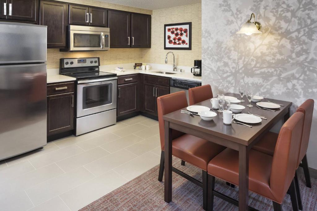 a kitchen with a table with chairs and a kitchen with stainless steel appliances at Residence Inn Minneapolis Downtown/City Center in Minneapolis