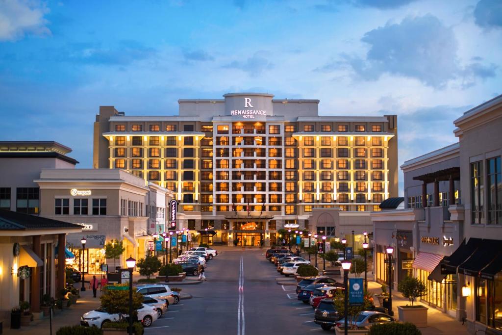 ein großes Gebäude mit Autos auf einem Parkplatz in der Unterkunft Renaissance Raleigh North Hills Hotel in Raleigh