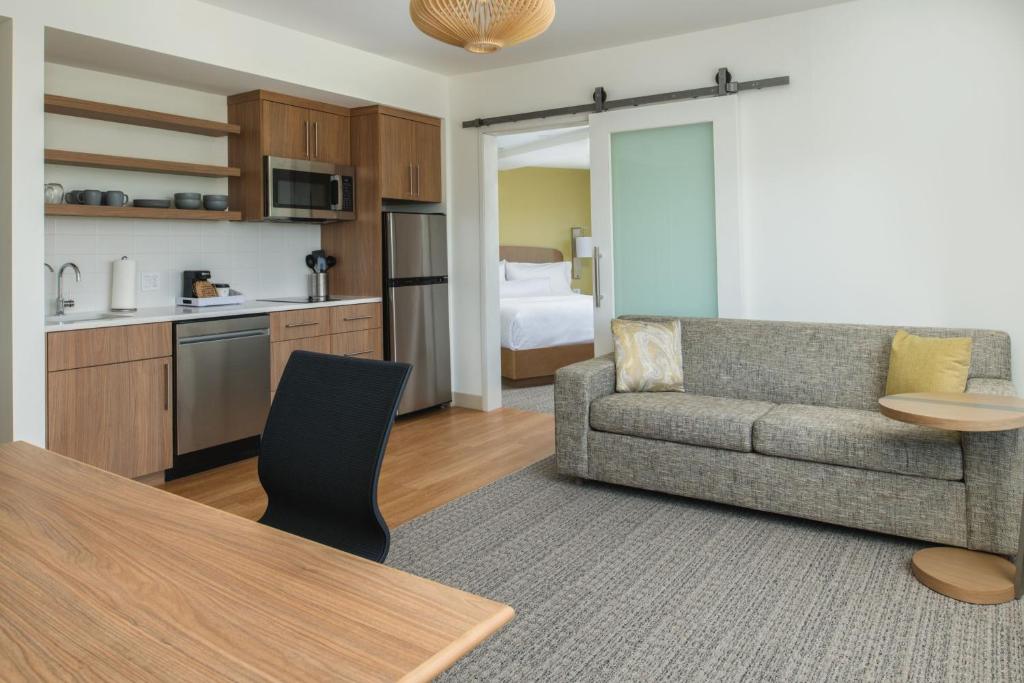 Element San Jose Milpitas في ميلبيتاس: غرفة معيشة مع أريكة ومطبخ مع سرير