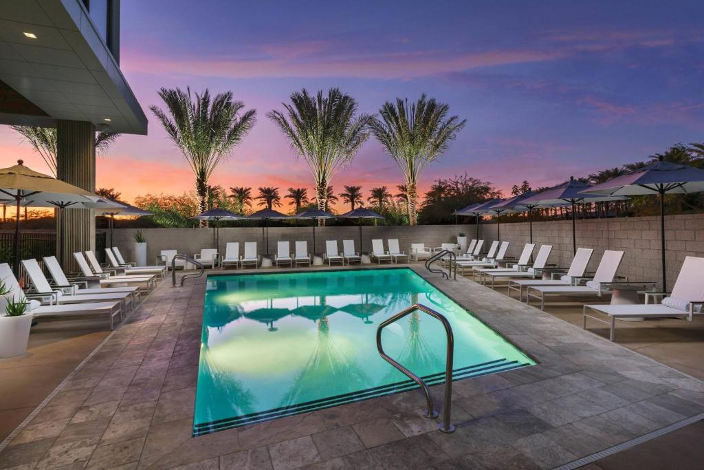 a pool at a hotel with chairs and a sunset at AC Hotel by Marriott Scottsdale North in Scottsdale
