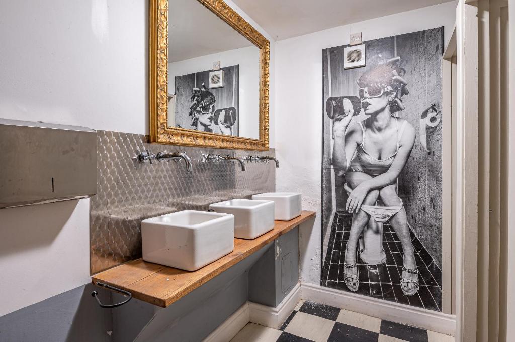 a bathroom with three sinks and a picture of a man at Moonfleet Guest House in Skinningrove