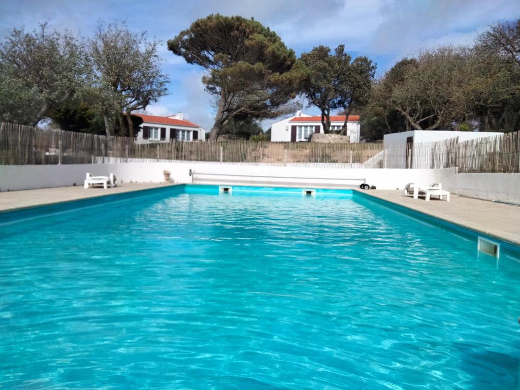 une piscine avec de l'eau bleue dans une cour dans l'établissement Les Pieds Dans L'eau Accés direct à la plage, à La Cotinière