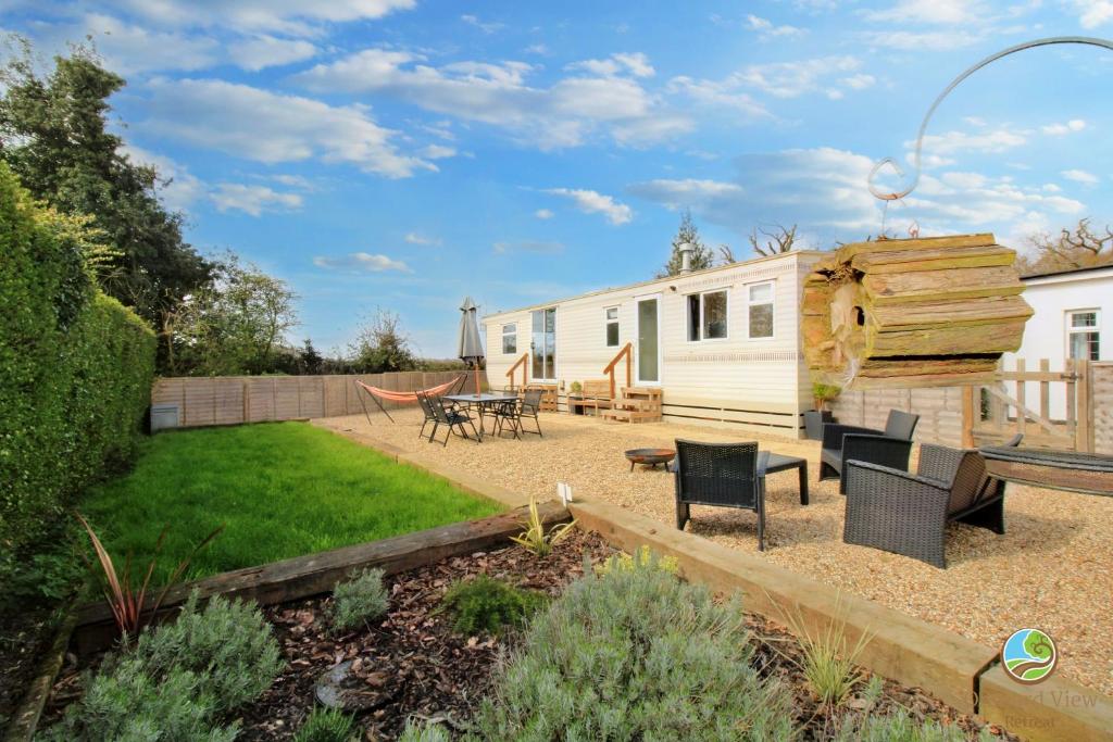a backyard with a tiny house with a table and chairs at Orchard View Retreat - Dog friendly, enclosed private garden with weather dependant hot tub - Not on a holiday park in Little Clacton