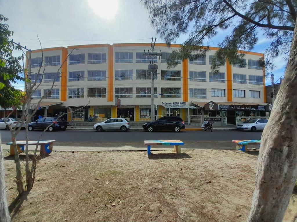 un gran edificio con coches estacionados frente a él en Lebanon Praia Hotel, en Tramandaí