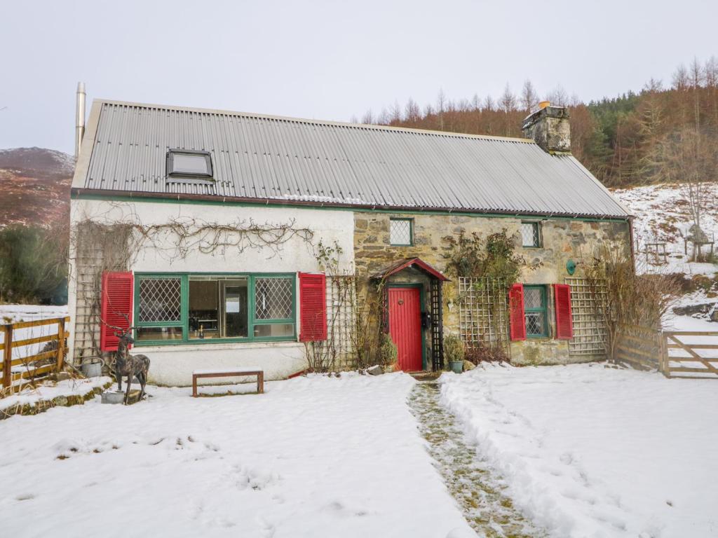 a stone house with red doors in the snow at The Old Mill in Beauly