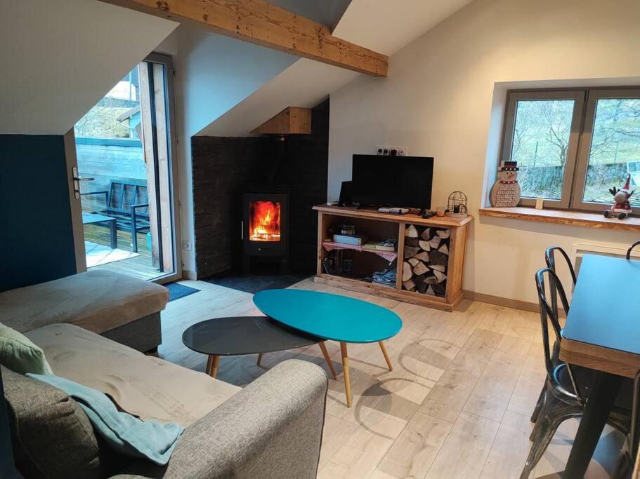 salon ze stołem i kominkiem w obiekcie Chez Alixe - Appartement avec terrasse w mieście Gérardmer