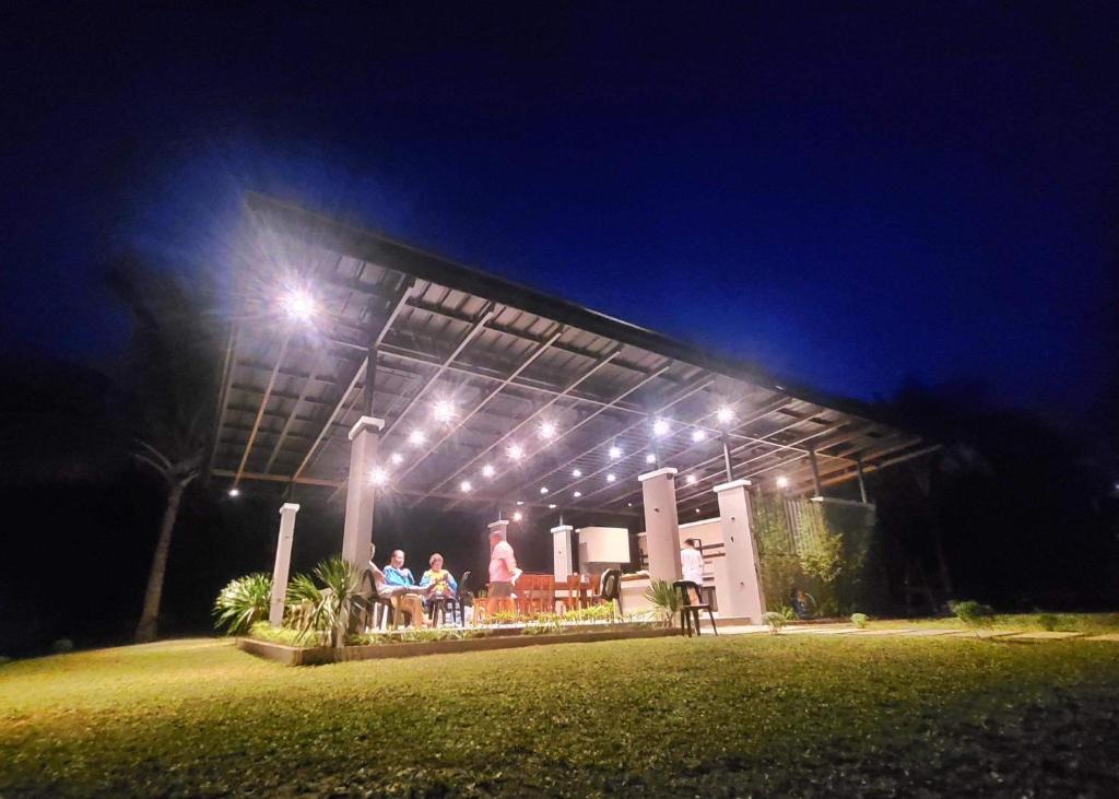 a group of people sitting under a building at night at Tranquille Campsite in San Isidro