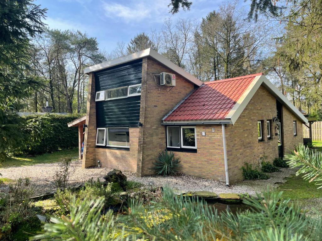 una pequeña casa de ladrillo con techo rojo en Boshuis met erg veel luxe, en Rheezerveen