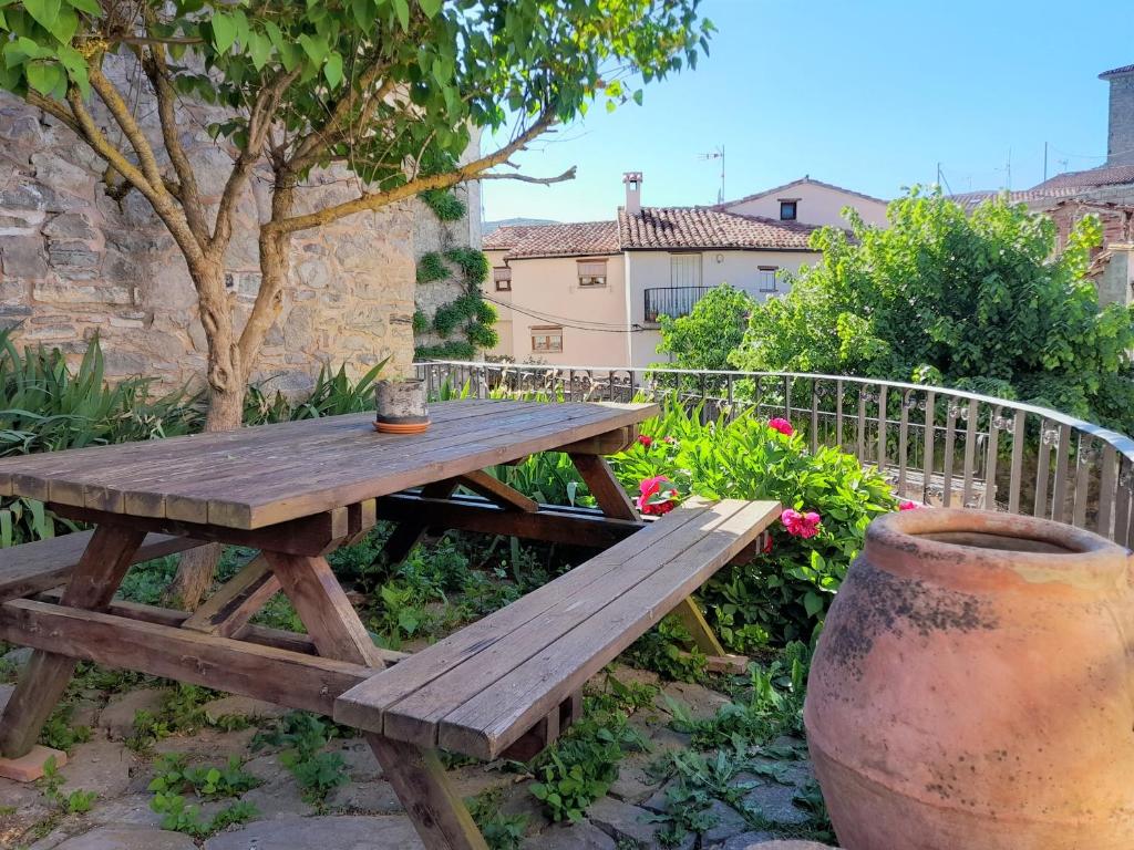 una mesa de picnic de madera en un jardín con un jarrón en Casasdetrevijano Cañon del rio leza en Soto en Cameros