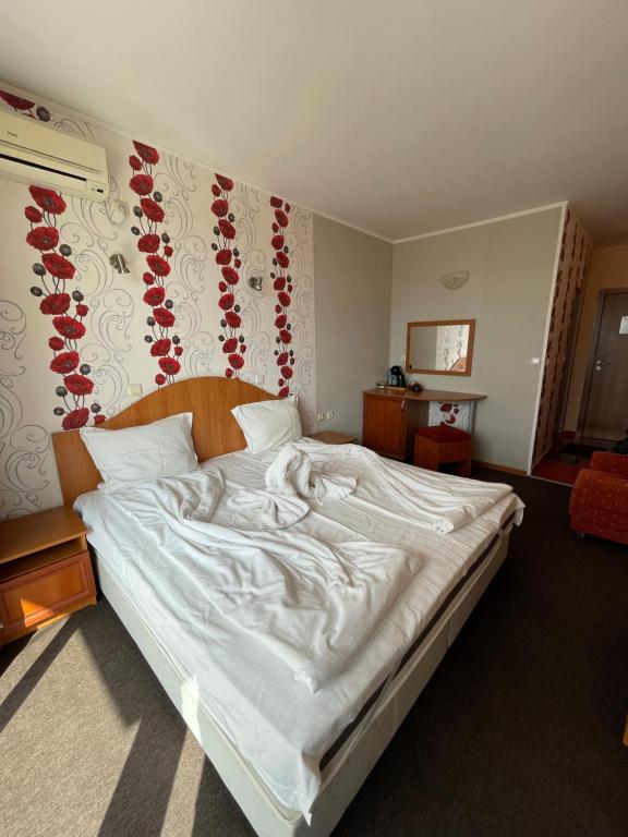 a bedroom with a large white bed with red flowers on the wall at Family hotel Deykin in Sunny Beach