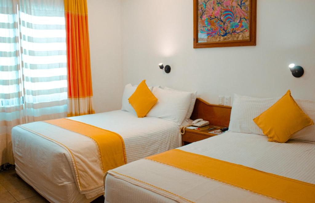 Habitación con 2 camas en naranja y blanco en Hotel Oaxaca Real, en Oaxaca City
