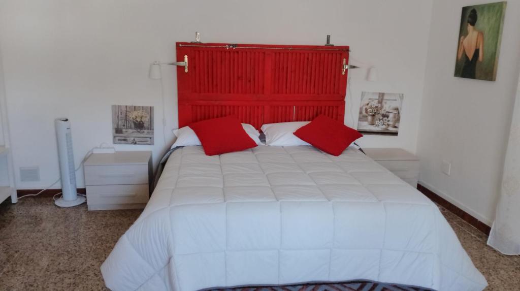 um quarto com uma grande cama branca com almofadas vermelhas em L' acero rosso em Miglianico