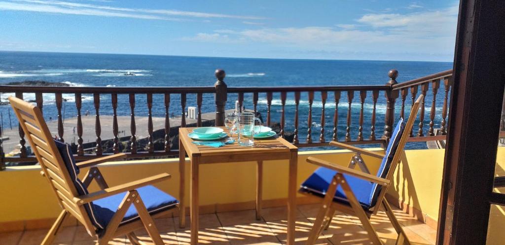 een tafel en stoelen op een balkon met uitzicht op de oceaan bij Marjul in Garachico