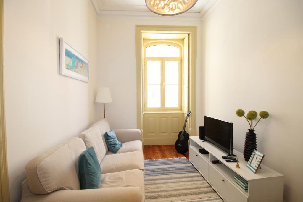 a living room with a couch and a television at Casa 11 Cravos in Figueira da Foz