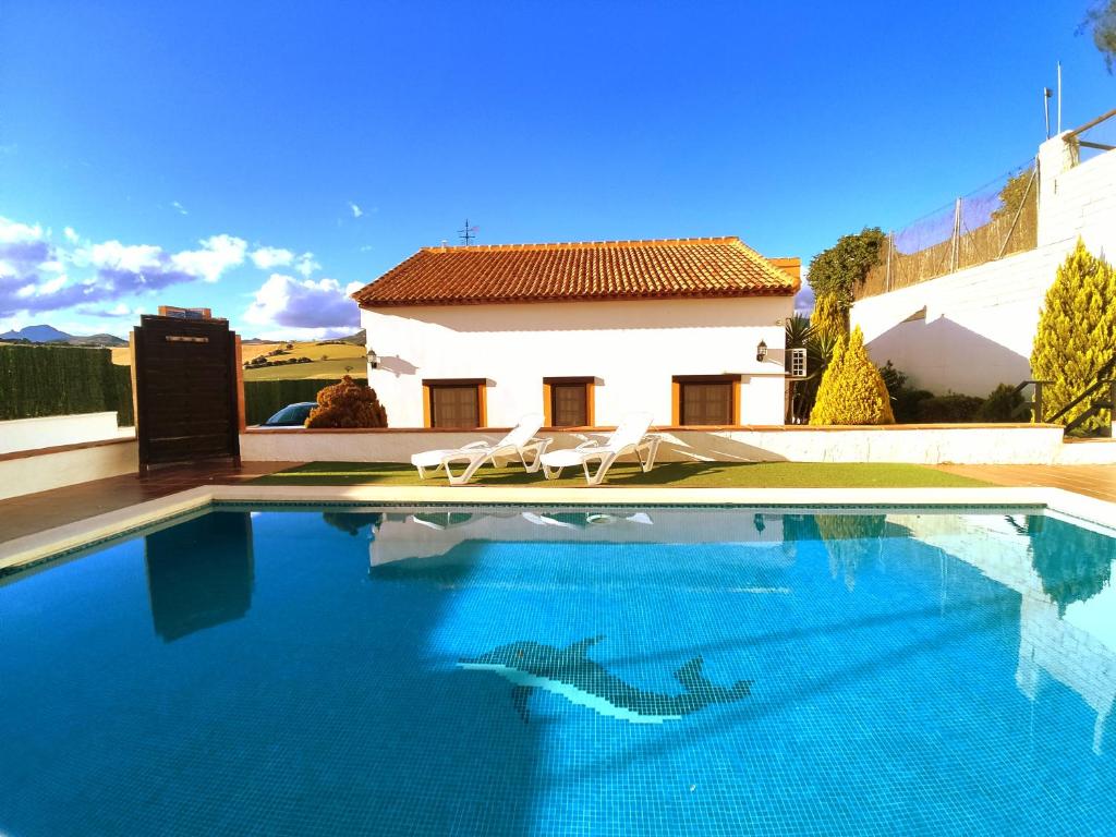 una piscina con due sedie e una casa di Only4you Country House Perfect location to visit Andalucia a Casabermeja
