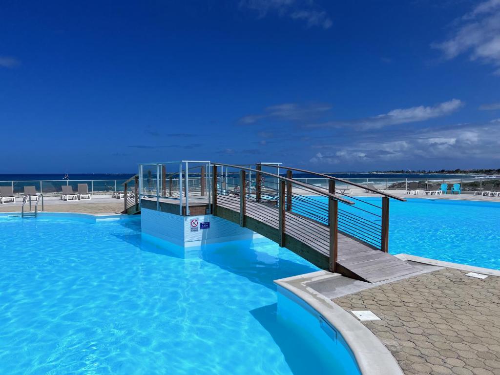 un puente sobre una gran piscina de agua azul en Orient Bay Studio SABA Face à la Mer, en Saint Martin