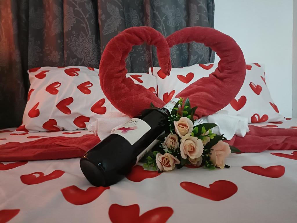 a bottle of wine on top of a bed with hearts at Amigas Lodge Transient in San Felix