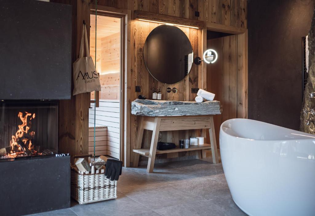a bathroom with a tub and a mirror and a fireplace at Amus Chalets Dolomites - Luxury Chalets South Tyrol in Anterselva di Mezzo