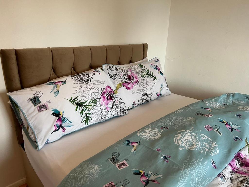 Una cama con dos almohadas florales encima. en The Grande Residence - Close to Central London & Next to Northfield Tube station, en Hanwell