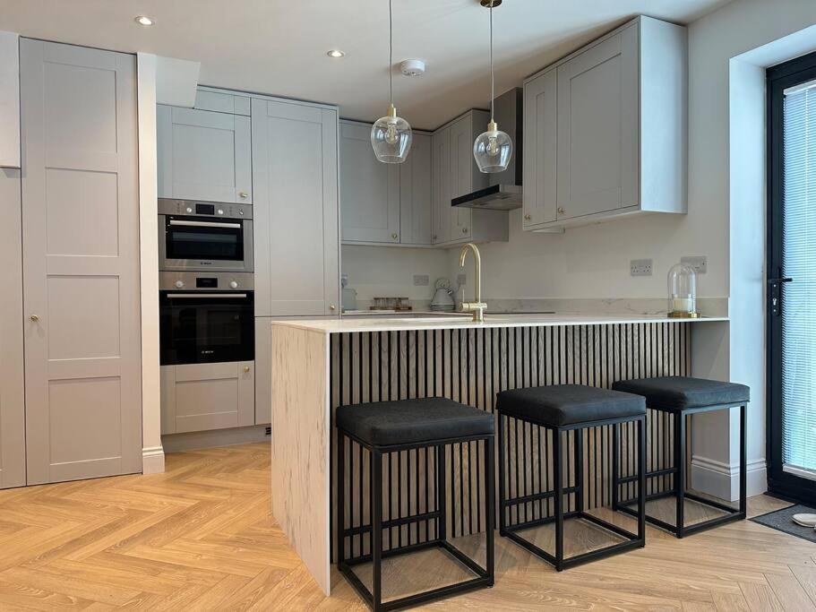 a kitchen with white cabinets and black stools at Brand New Luxury 2 Bedroom House in Parkstone